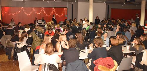 Students are sitting at tables in the Dining hall, which is decorated with Christmas lights